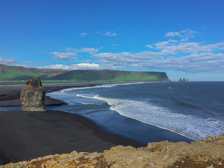 landscape view of a black sand beach along a rocky coastline