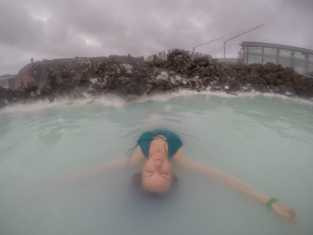 Girl in a green suit floating in the blue lagoon Iceland