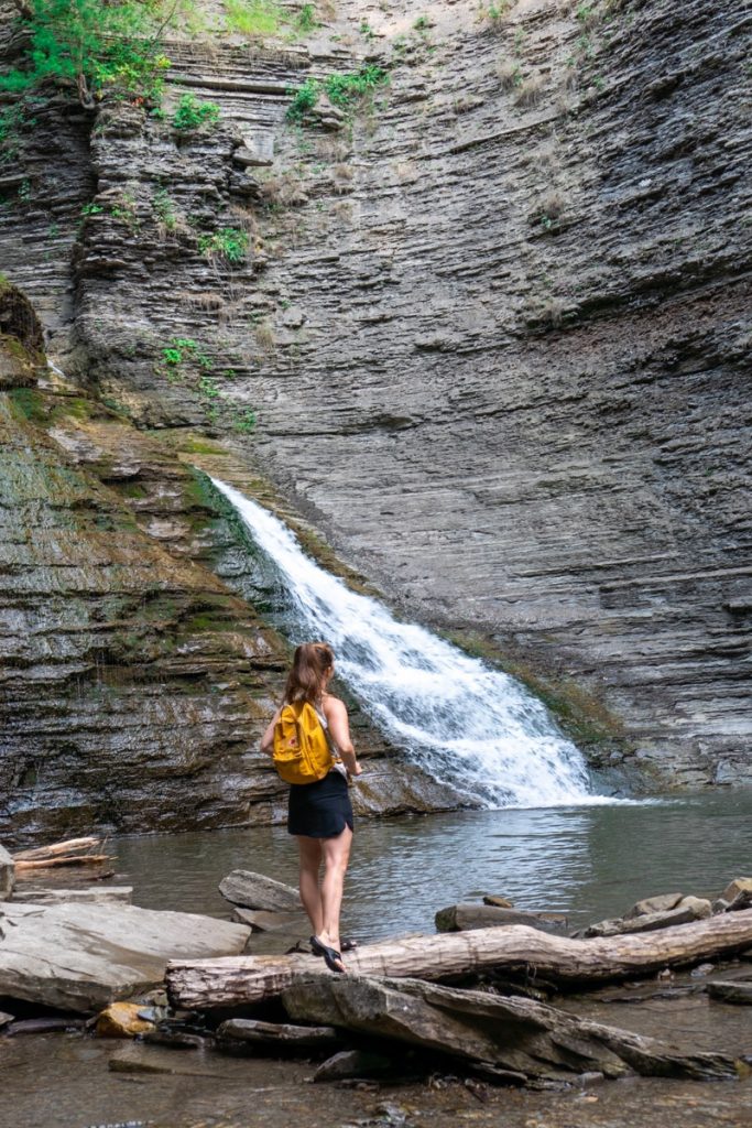 Girl standing on the edge of a natural waterfall pool.