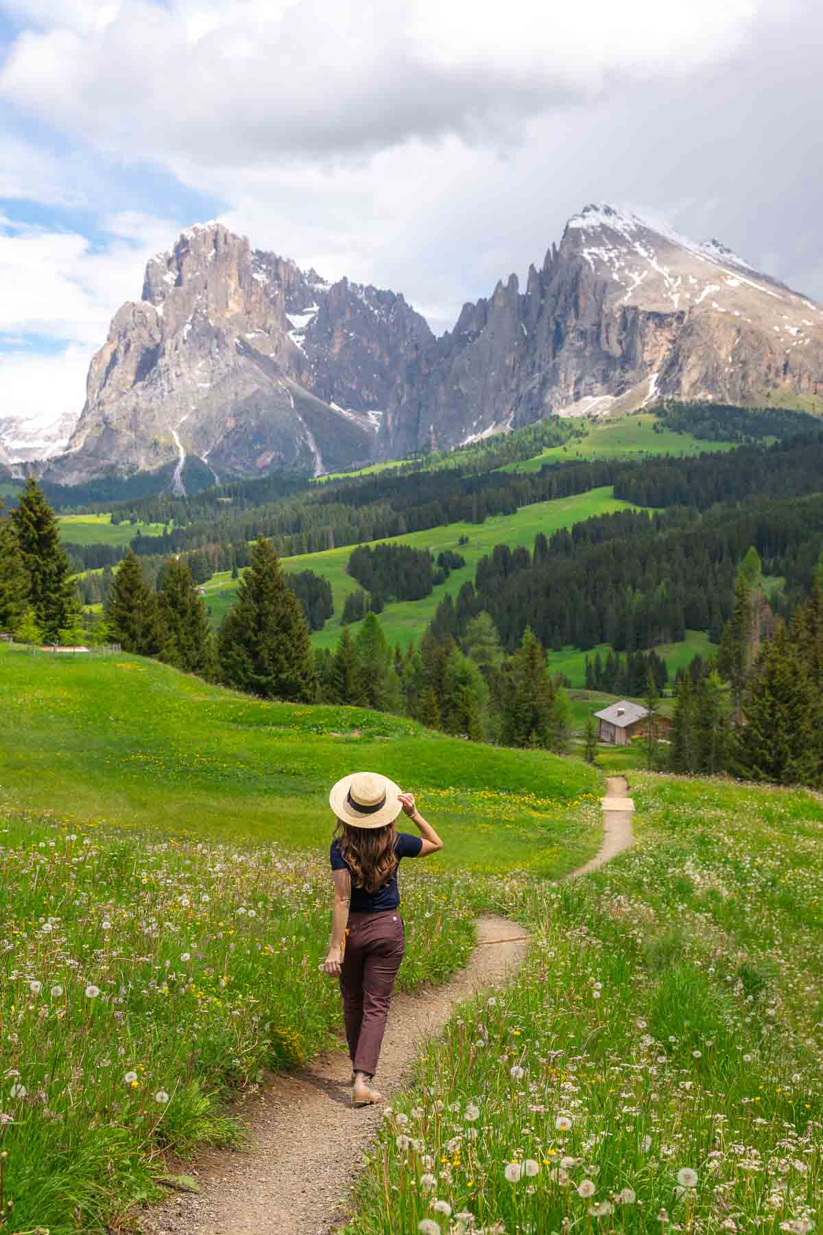 Sam walking down dirt path with mountains in the background.