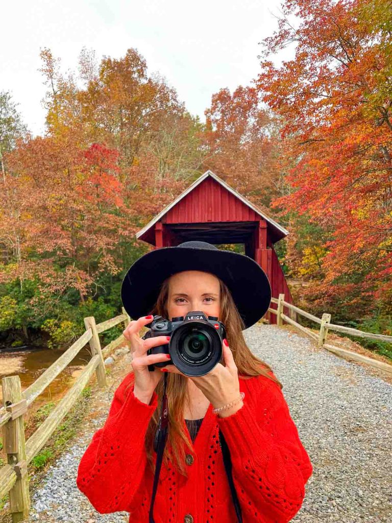 Sam standing in front of covered bridge with camera.