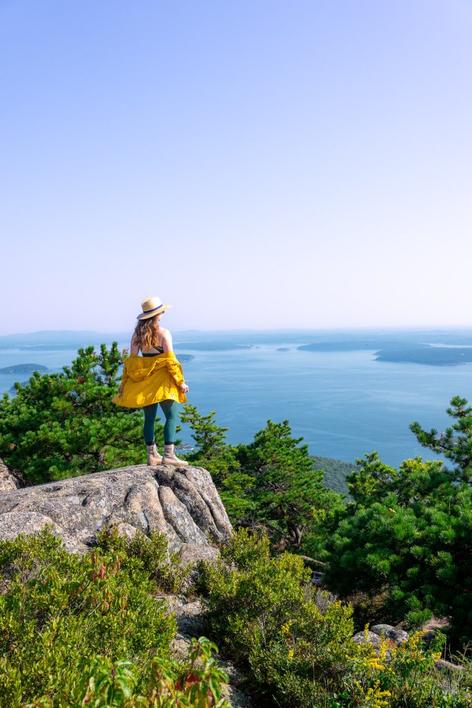 girl in a yellow jacket standing on a cliff