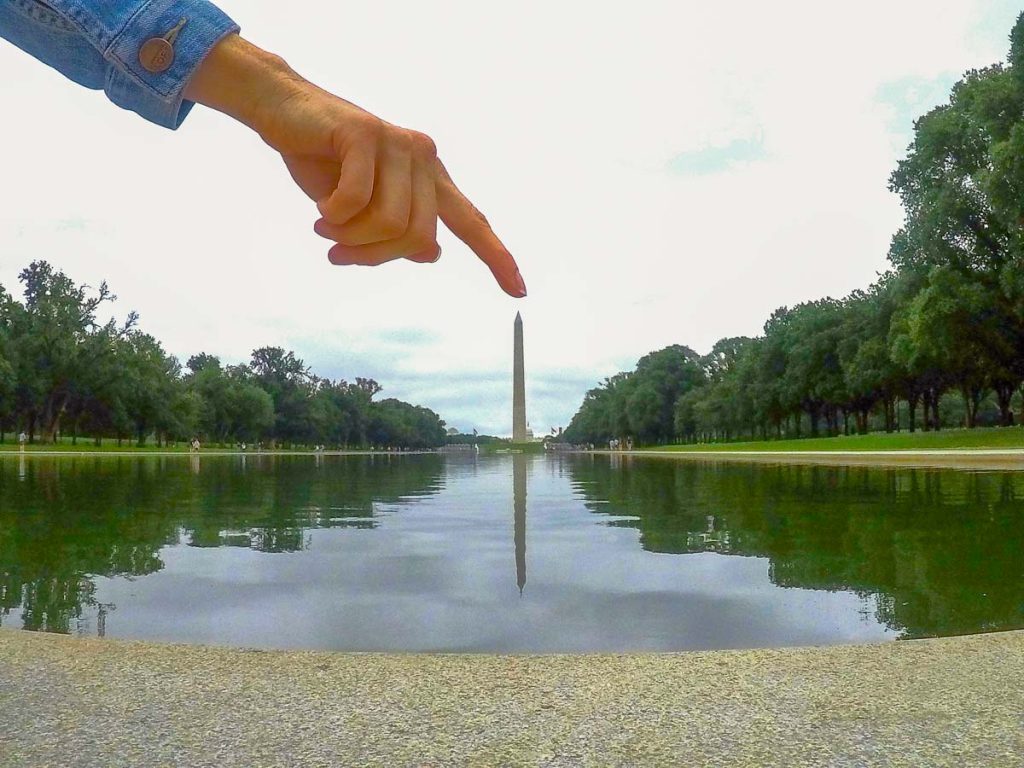 A hand pointing to the top of the Capital Building.
