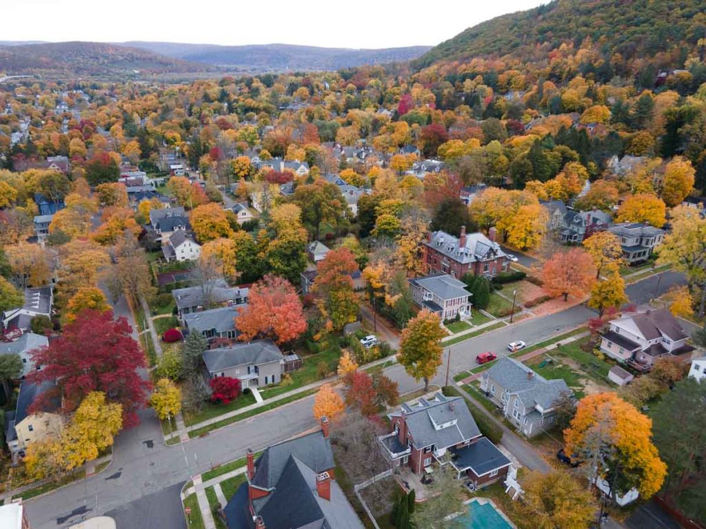 Aerial view of orange, red and yellow trees in a residential neighborhood.