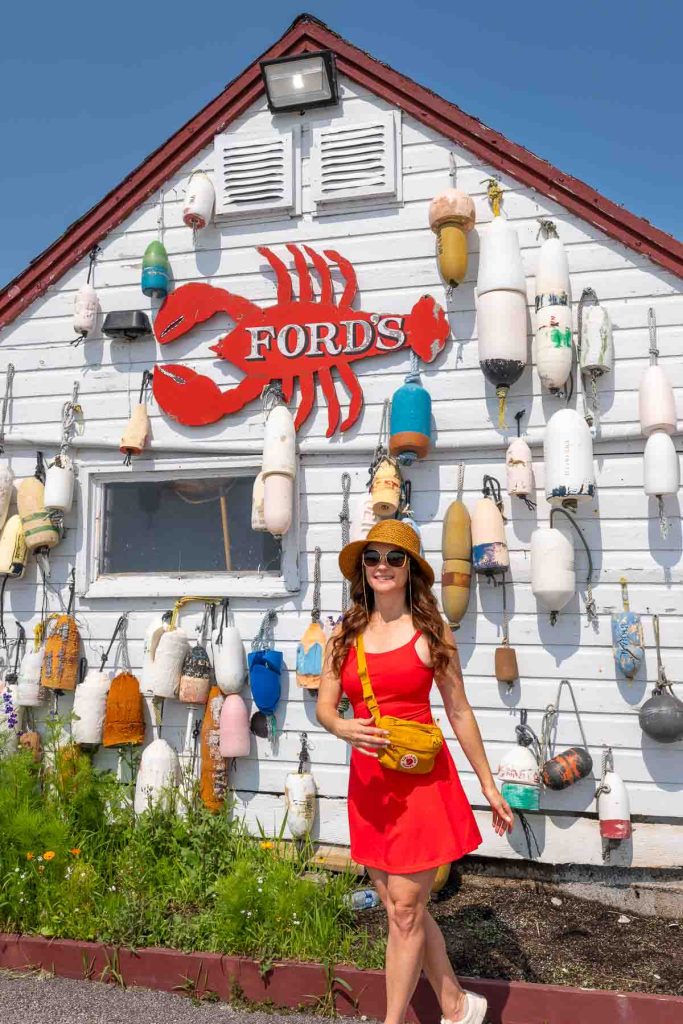 Girl in a red dress standing in front of a white wooden building with a red lobster sign overhead.