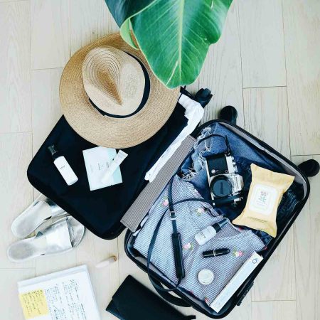 suitcase filled with a hat, clothes, camera, travel wipes.