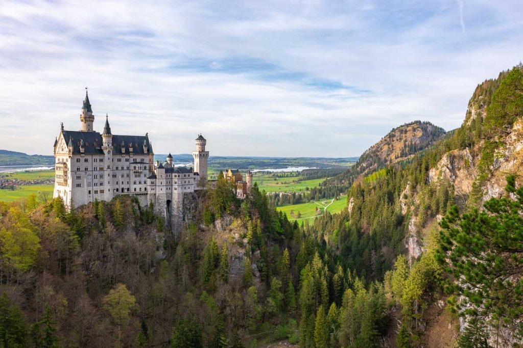 A castle on a hill surrounded in green trees.