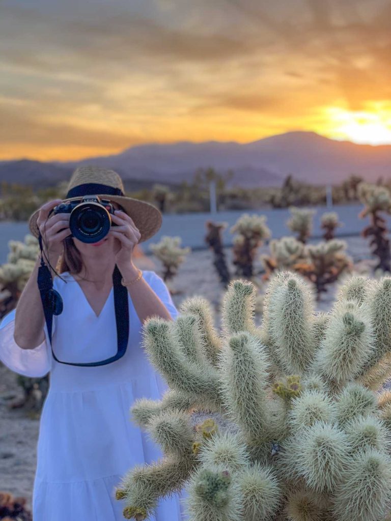 Girl in a white dress with a camera to her face.