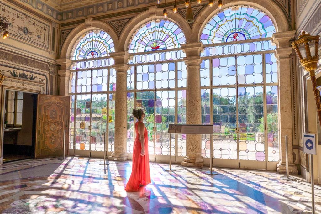 Sam standing in front of a window of stained glass.